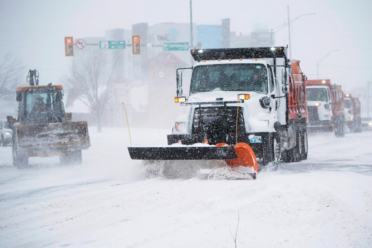 Vehicles work to clear an intersection during a winter storm Sunday, February 14, in Oklahoma City.