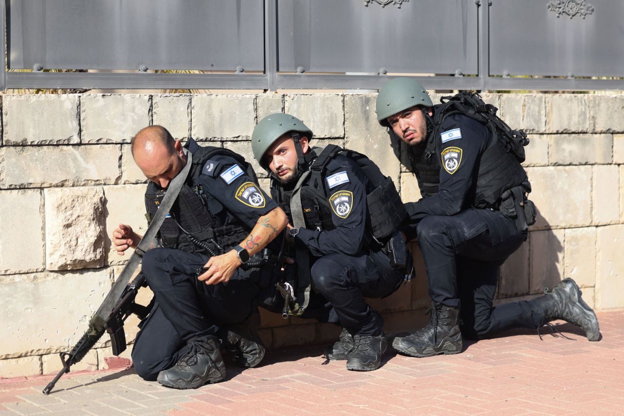 Members of the Israeli frorces take cover on the side of a street in Ashkelon, Israel, on October 7, 2023.