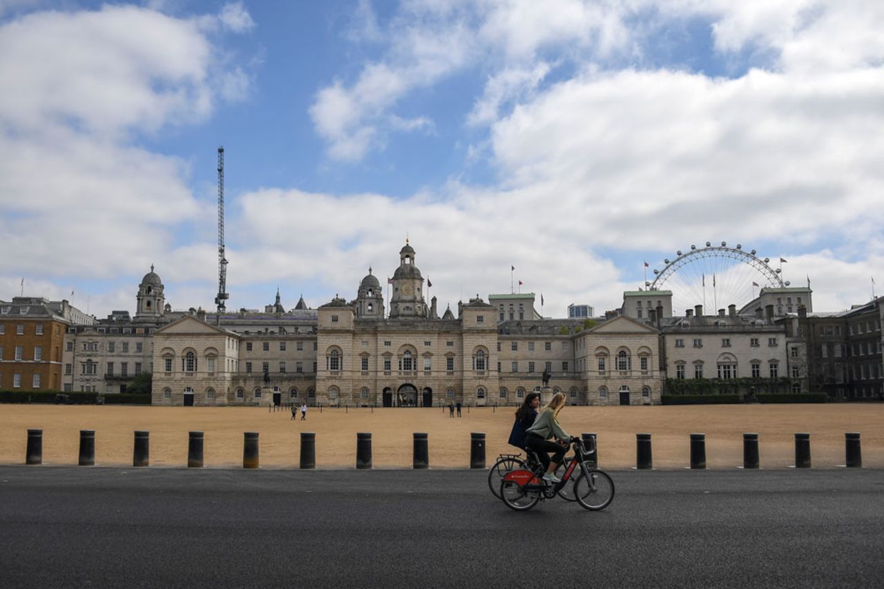 Two women ride bicycles past the Horse Guards Parade, during lockdown due to the coronavirus outbreak, in London, on Saturday, April 25.