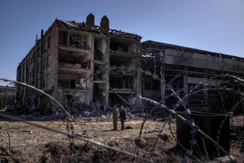 People stand beside damaged buildings at the Vizar company military facility on the outskirts of Kyiv, Ukraine on April 15. 