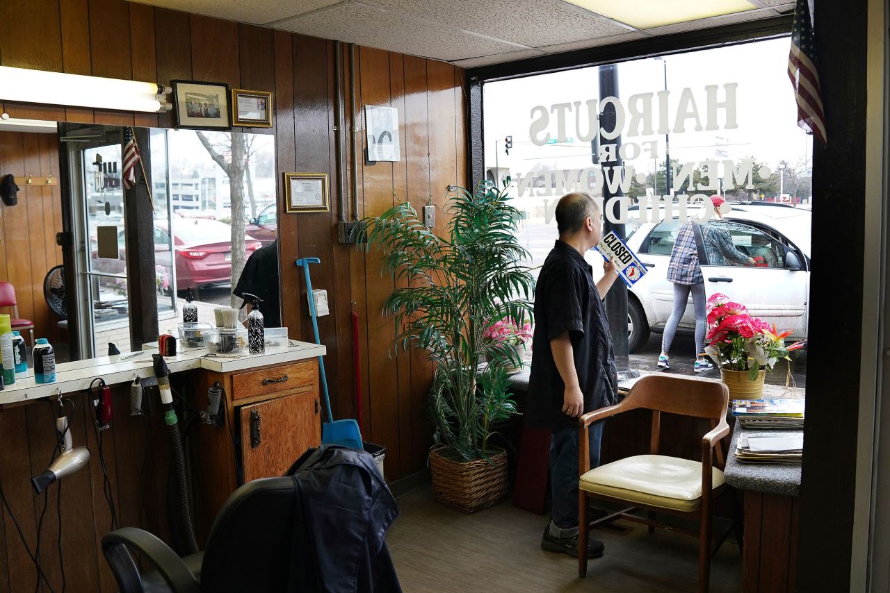 Mike Stevenson flips his barber shop sign to closed in Columbia Heights, Minnesota, on Wednesday, March 18.