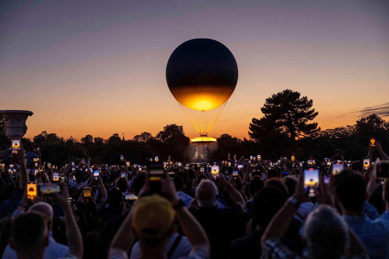 Visitors take pictures of the Olympic cauldron after sunset on July 28. 