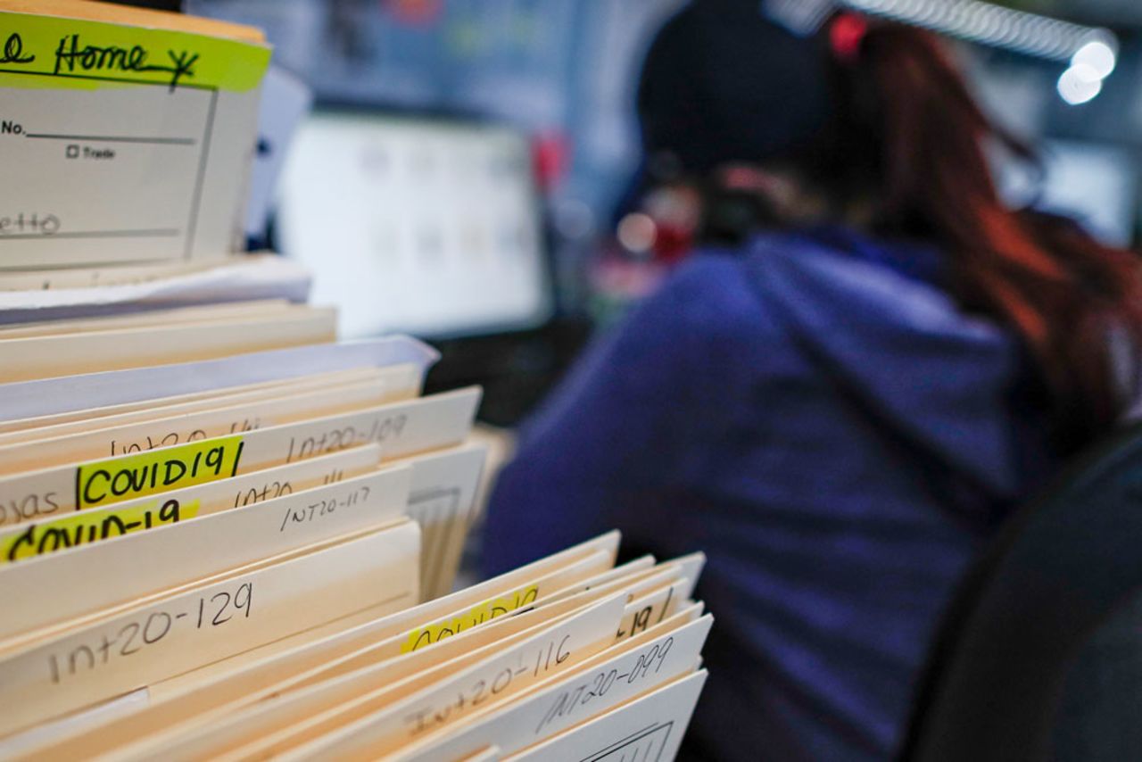 Folders containing information on those who died from Covid-19 are stacked among other client files while employee Gina Hansen works at the Daniel J. Schaefer Funeral Home on Thursday, April 2.