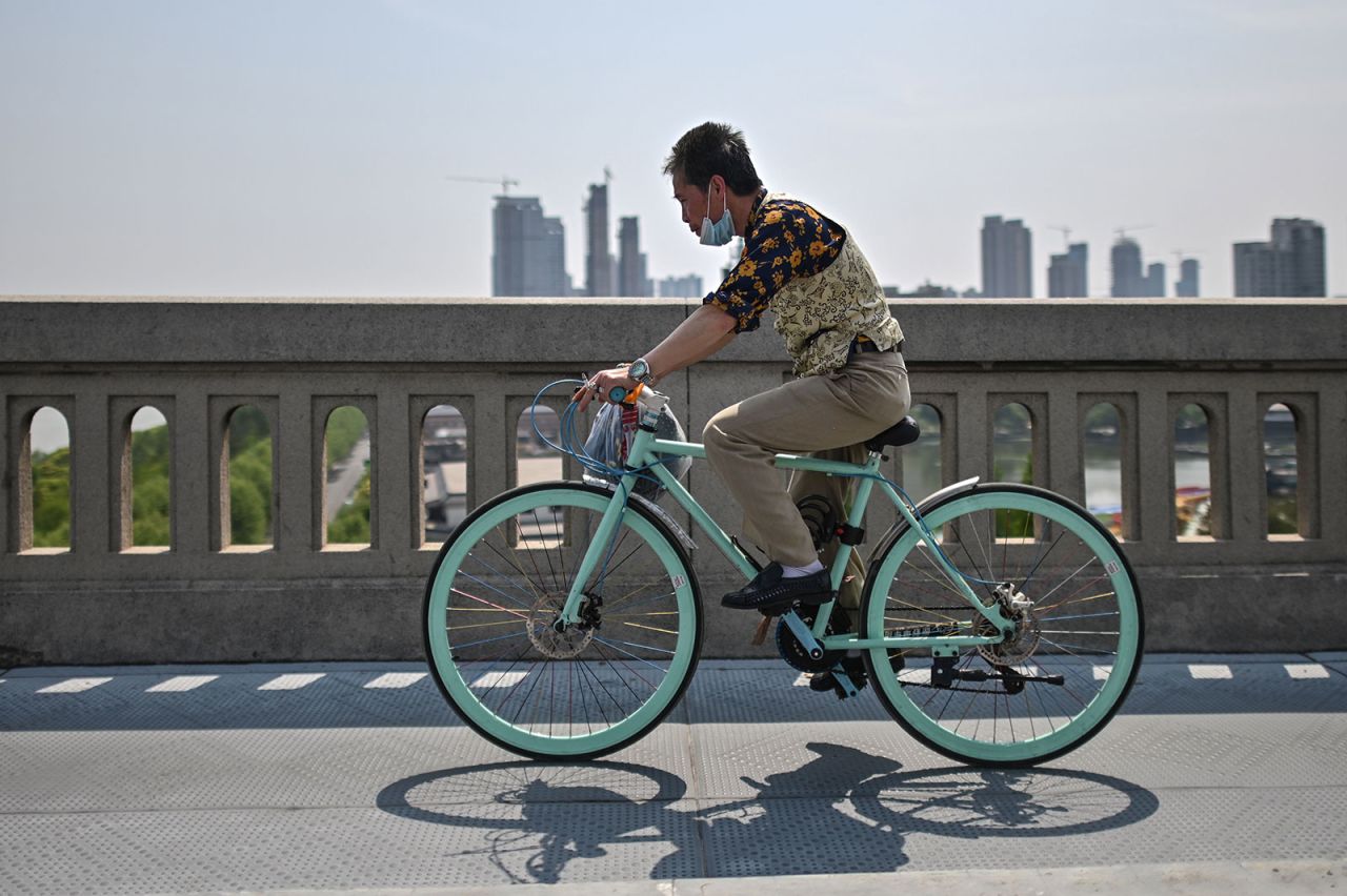 A man wearing a face mask rides a bicycle on Wuhan Bridge over the Yangtze river in Wuhan, in China's central Hubei province on April 16, 2020.