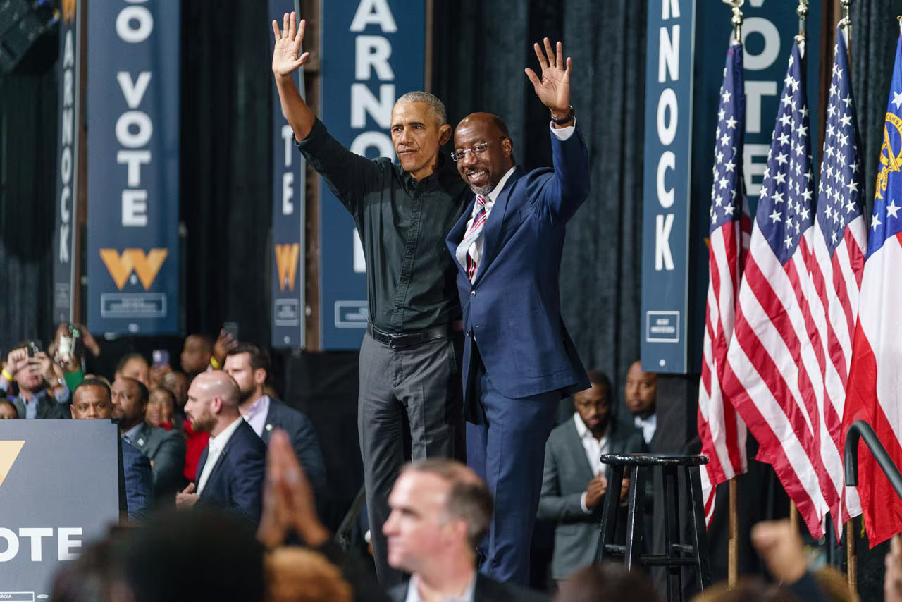 Former President Barack Obama, left, and Sen.Raphael Warnock wave to supporters during a campaign rally in Atlanta on Thursday, December 1. 