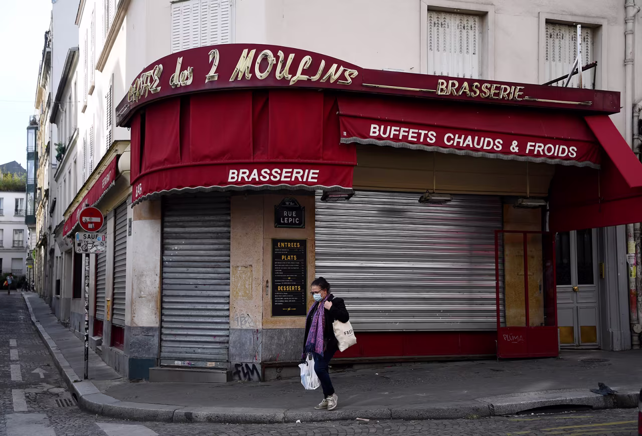 A woman walks past the entrance of the closed restaurant "Cafe des 2 Moulins" in Paris on April 21.