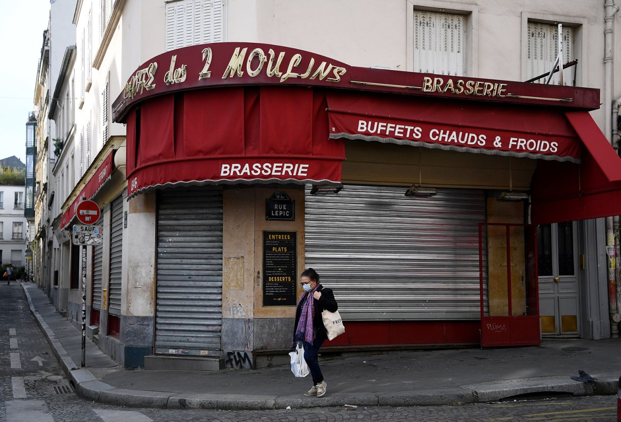A woman walks past the entrance of the closed restaurant "Cafe des 2 Moulins" in Paris on April 21.