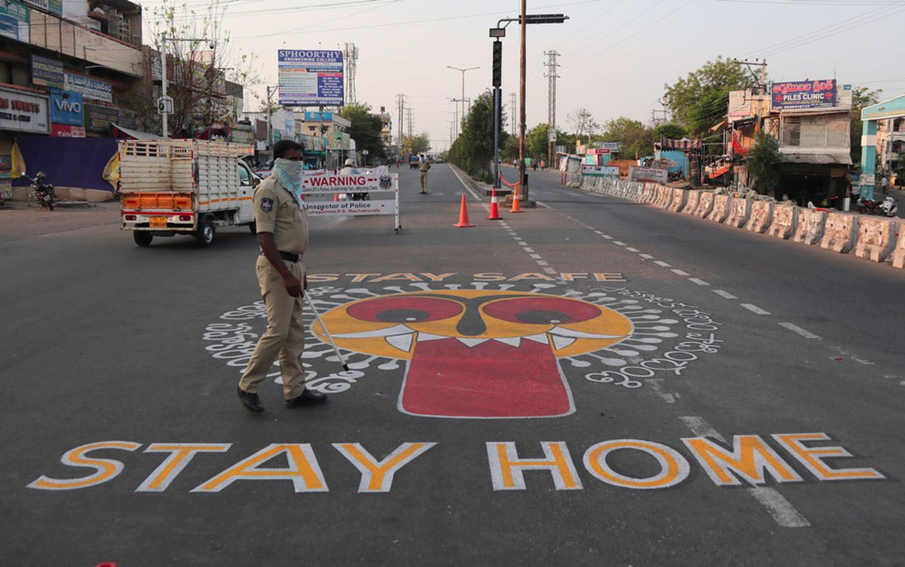 An Indian policeman walks past an art work displayed on a road urging people to stay home during lockdown in Hyderabad.