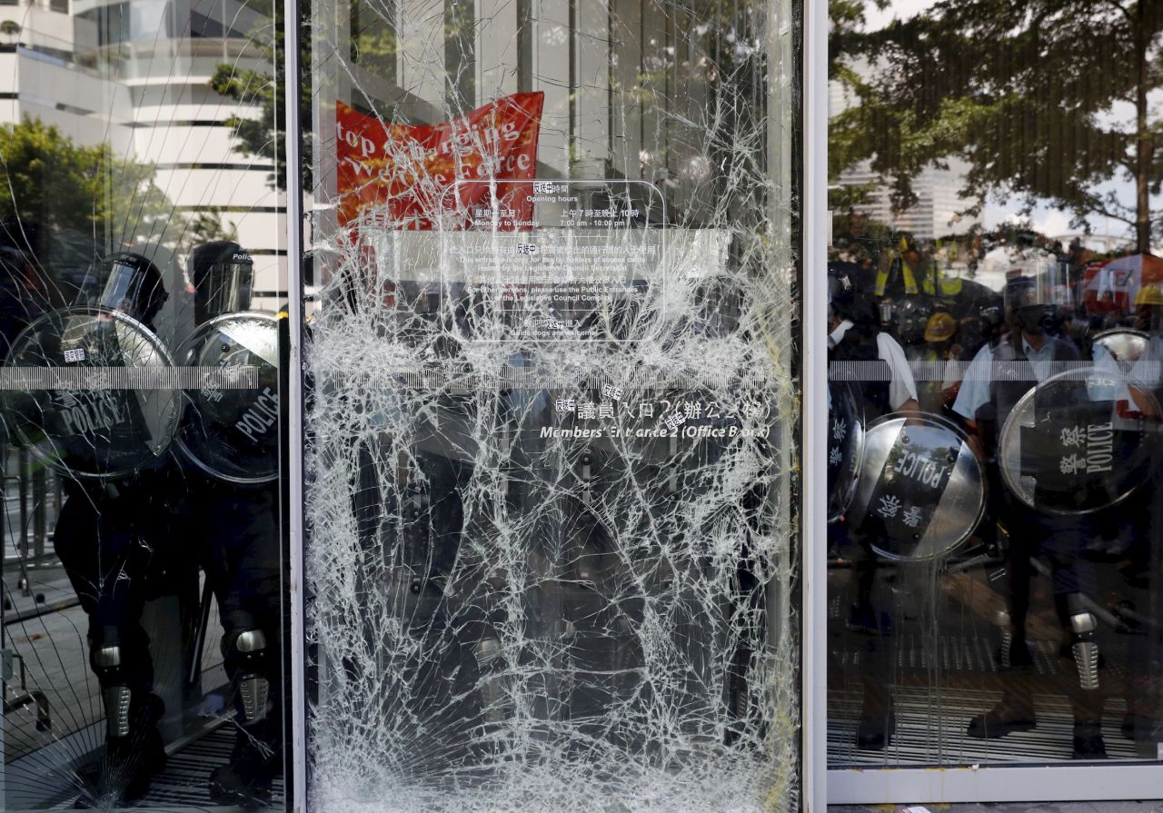 Police officers stand guard behind the cracked glass wall of the Legislative Council after protesters try to break into in Hong Kong on Monday, July 1.