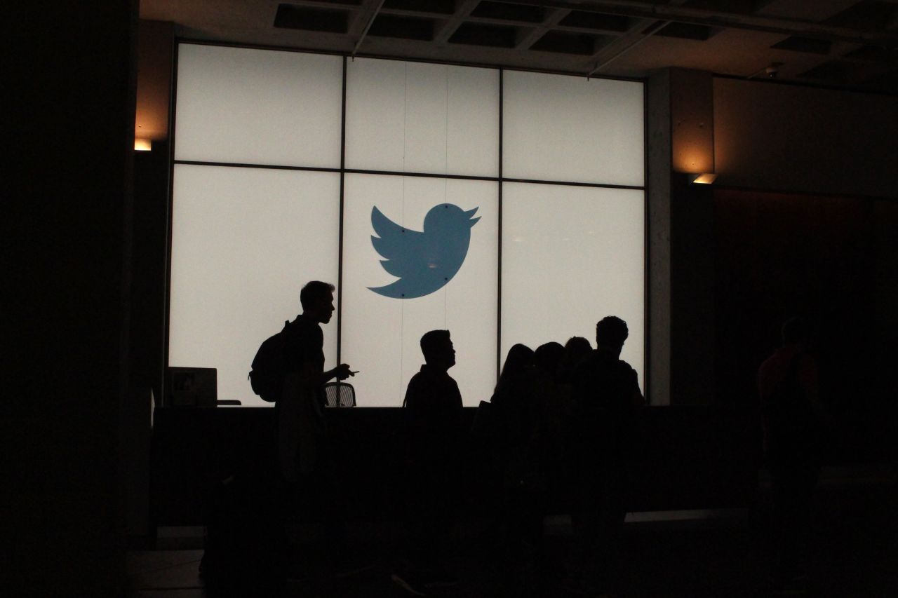 Employees walk past a lighted Twitter log as they leave the company's headquarters in San Francisco on August 13, 2019. 