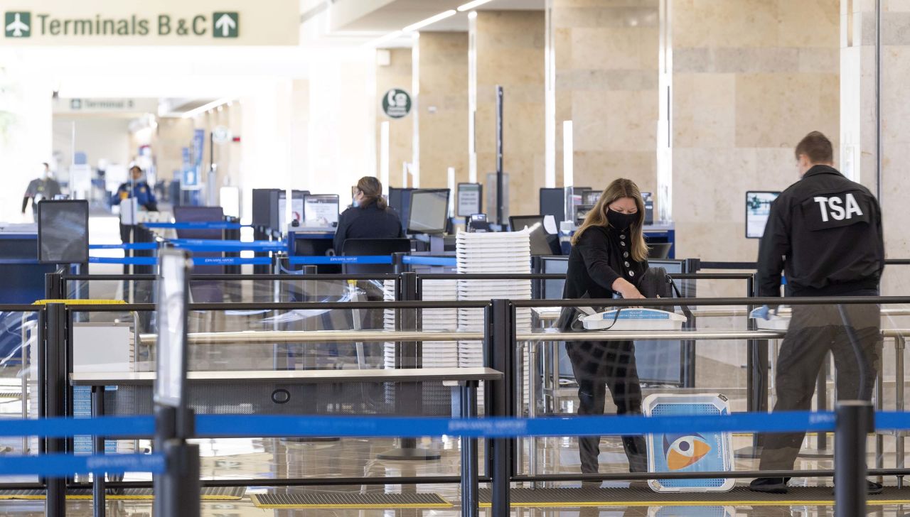 A TSA agent assists a traveler through a security checkpoint at John Wayne Airport in Santa Ana, California, on January 26. 