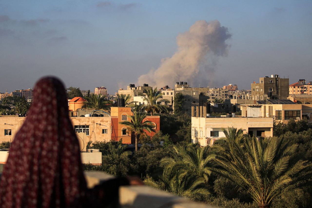 A Palestinian woman watches as smoke billows following an Israeli strike south of Gaza City, in the town of al-Zawaida in the central Gaza Strip, on June 11.