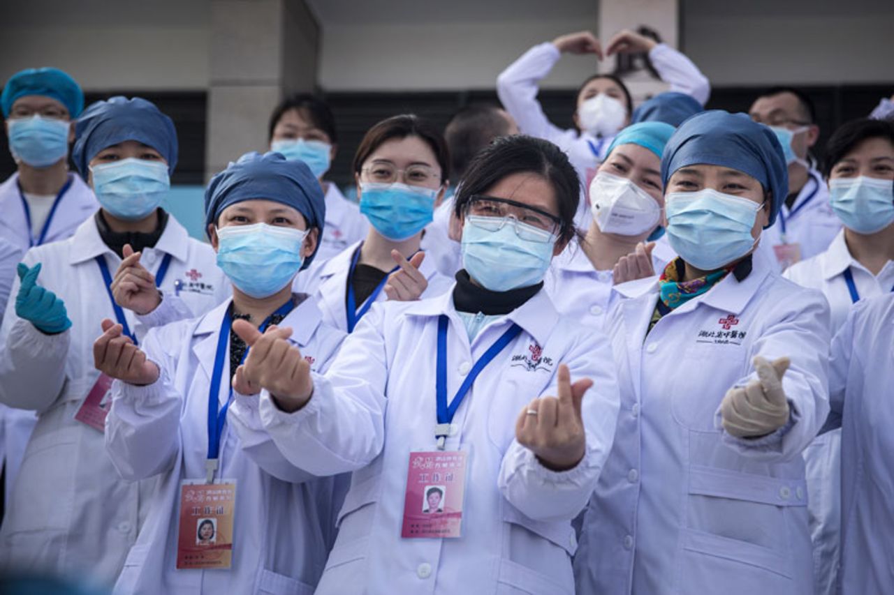 Medical professionals pose for photos as the last batch of coronavirus patients are discharged from Wuchang Fang Cang makeshift hospital on March 10, in Wuhan, Hubei province, China. 