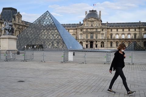 A woman walks in front of the Louvre museum on May 13 in Paris.