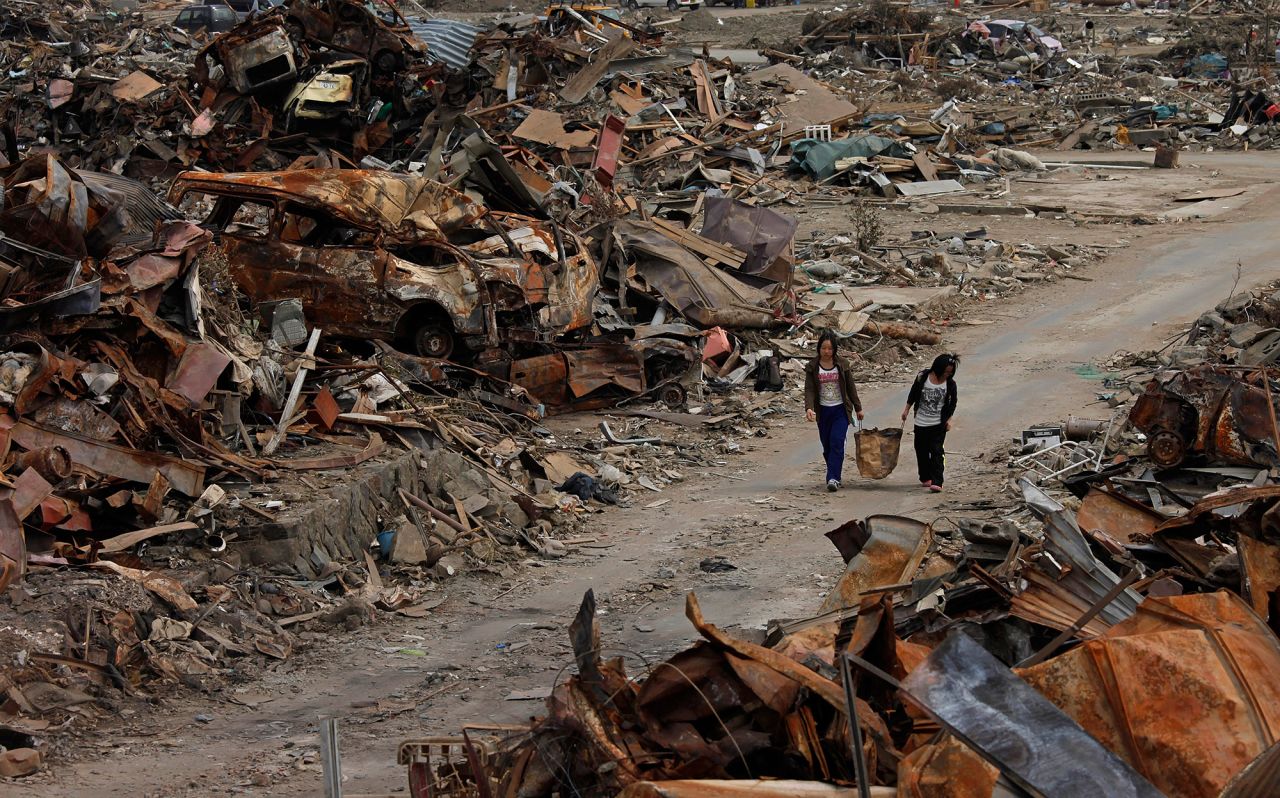 Two women walk past debris in an area devastated by the March 11 earthquake and tsunami in Ishinomaki, Japan, on April 7, 2011. 