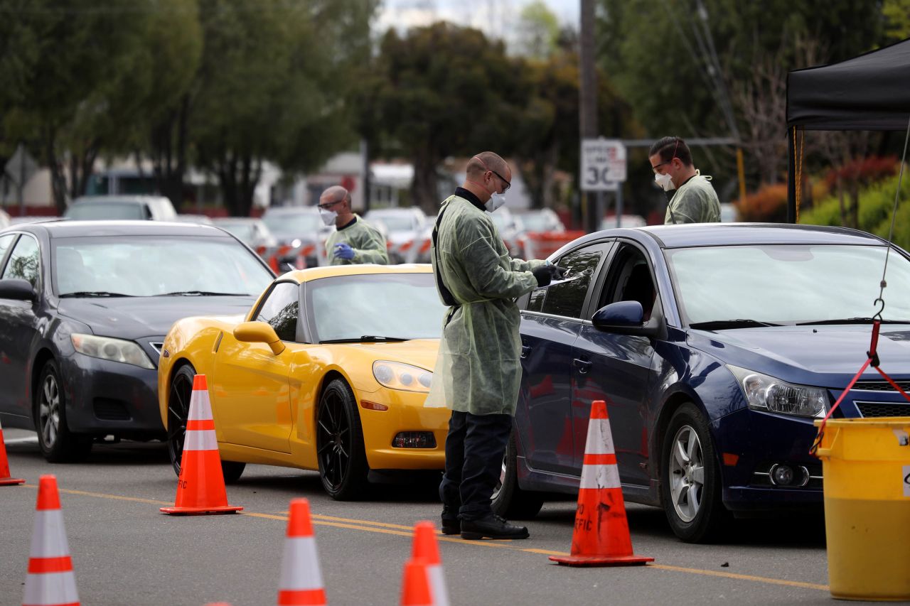 Firefighters screen people that are waiting in line to get a COVID-19 test at a free public testing station in Hayward, California, on March 24.