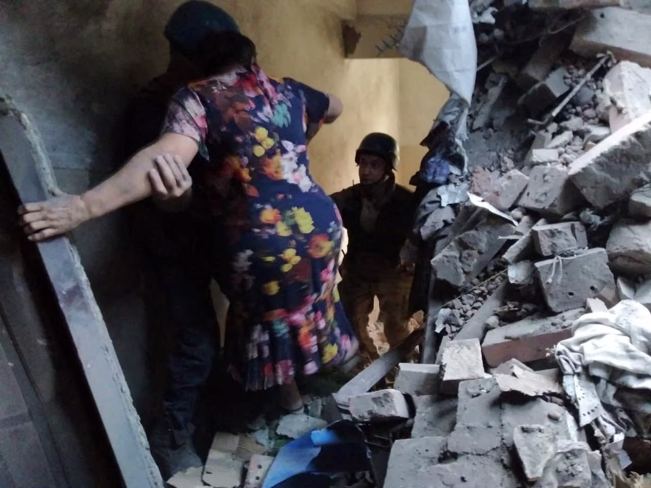 Rescuers help a woman evacuate from a residential building damaged by a Russian military strike in the town of Toretsk, Donetsk region, Ukraine, on July 28.