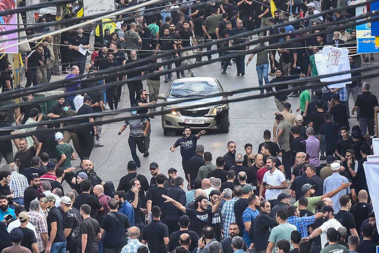 People react around a car after a reported explosion occurred during the funeral of those killed when hundreds of paging devices exploded across Lebanon the previous day, in Beirut's southern suburbs on September 18. 