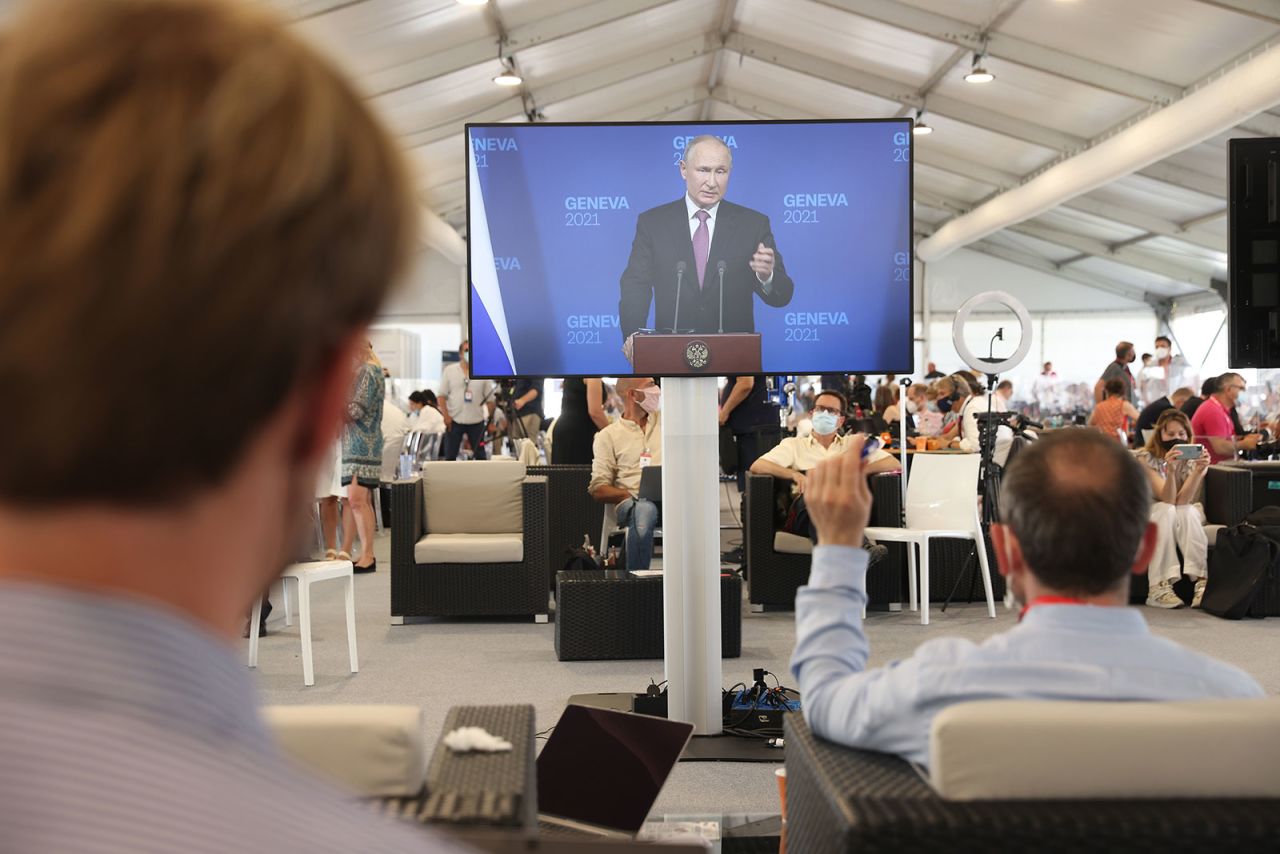 Journalists watch Russian President Vladimir Putin speak during a press conference from a media center in Geneva.