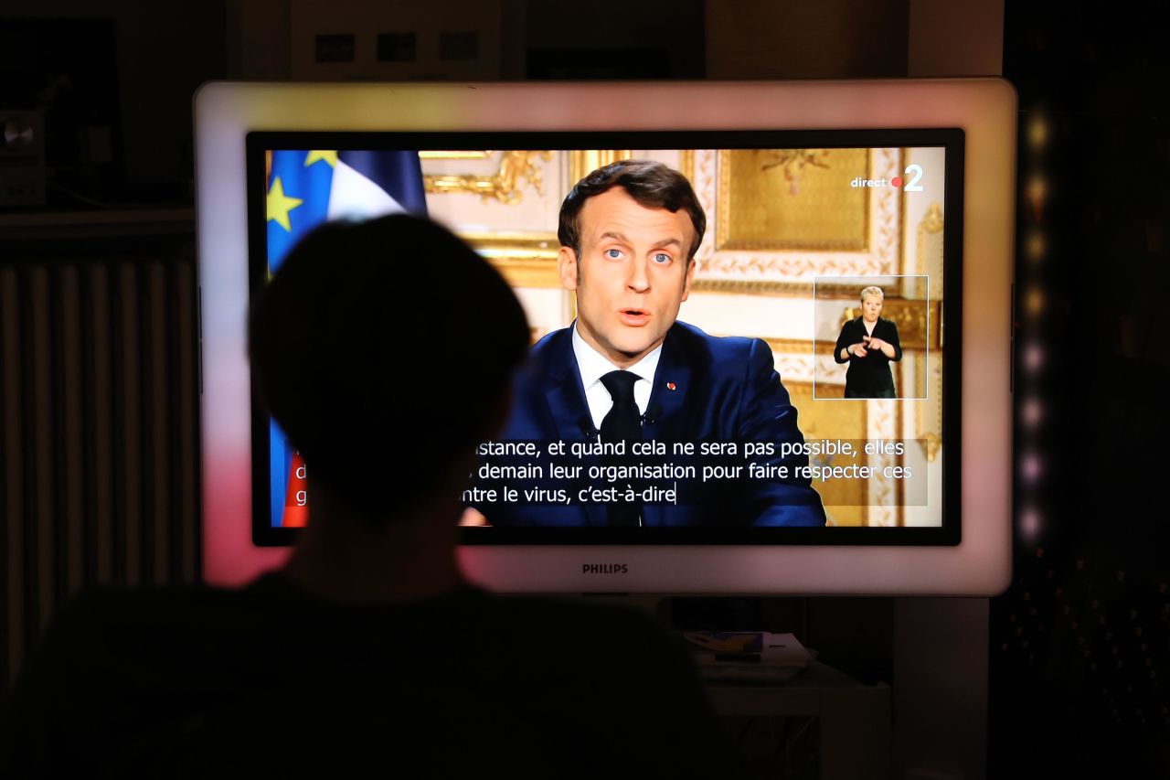 French President Emmanuel Macron is seen on a television screen on March 16 as he speaks during an address to the nation on the coronavirus outbreak.