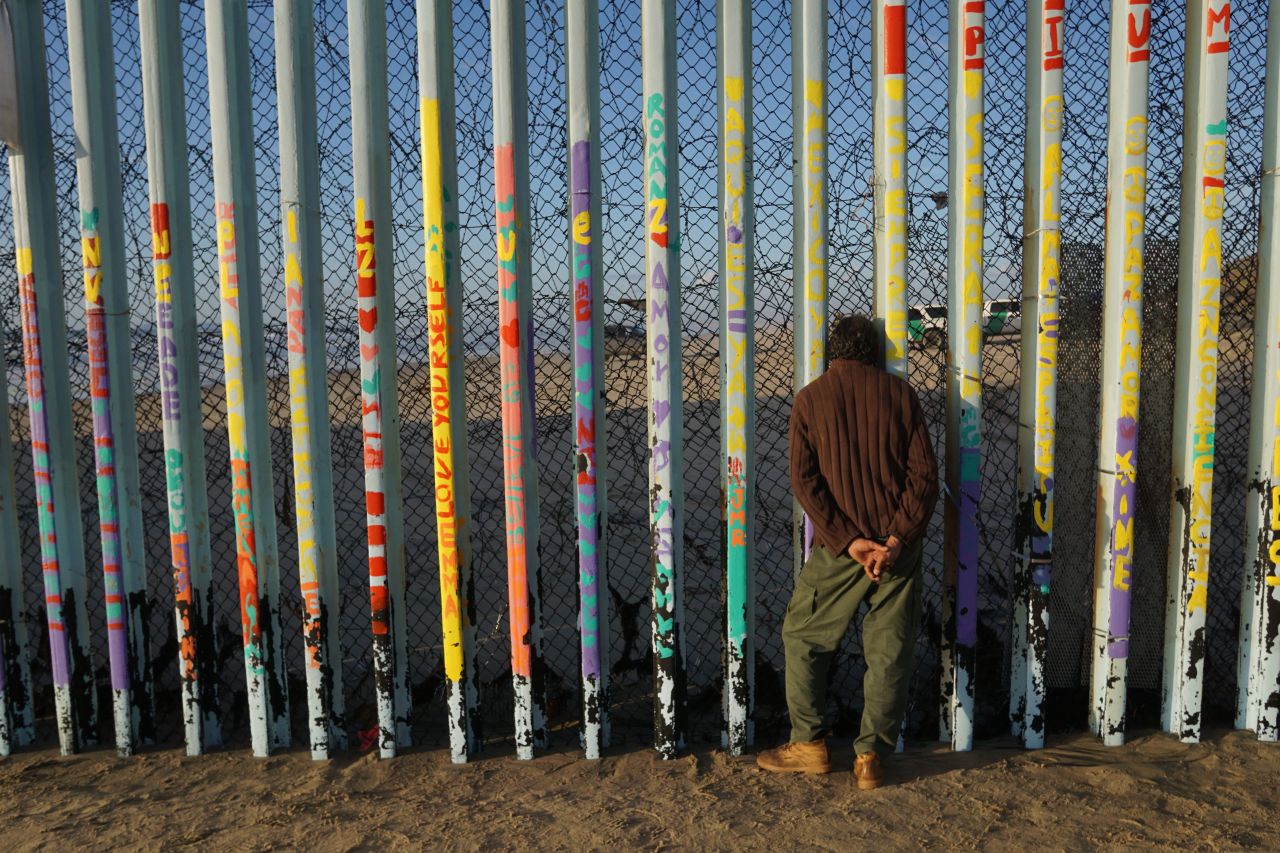 A man looks through the U.S.-Mexico border wall in Tijuana, Mexico, on Sunday. 