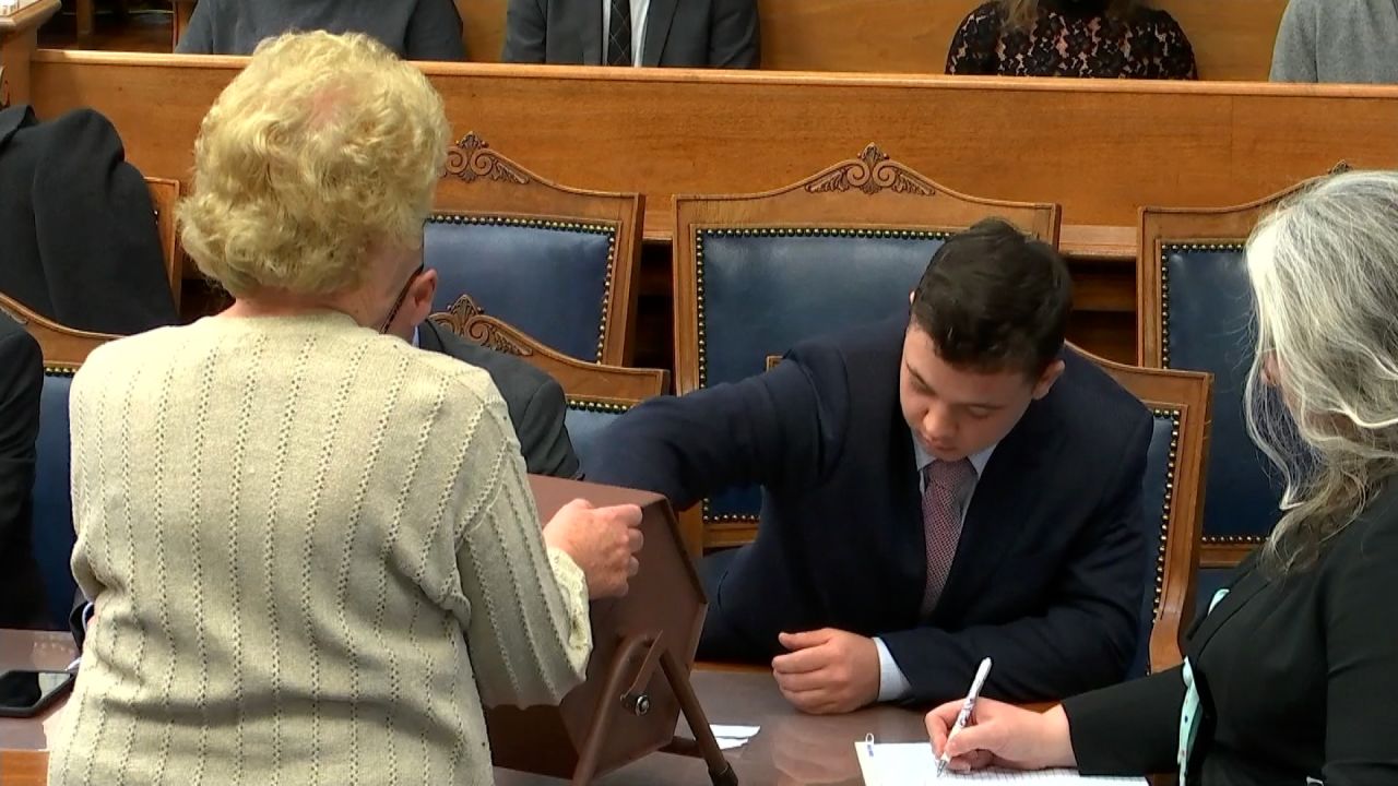 Rittenhouse reaches into the tumbler to pull out a juror number on Tuesday.