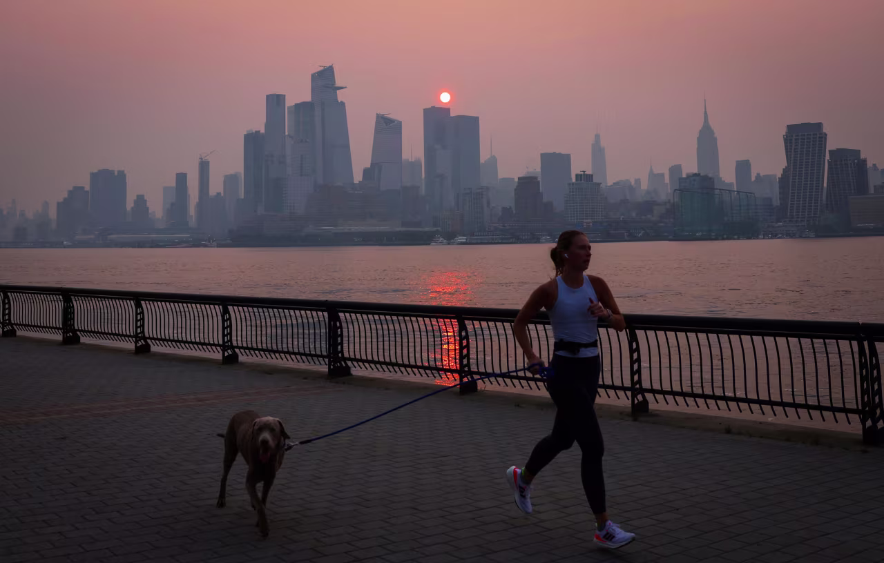 A woman jogs along the Hudson River as a smoky haze hangs over the New York skyline shortly after sunrise on Wednesday.