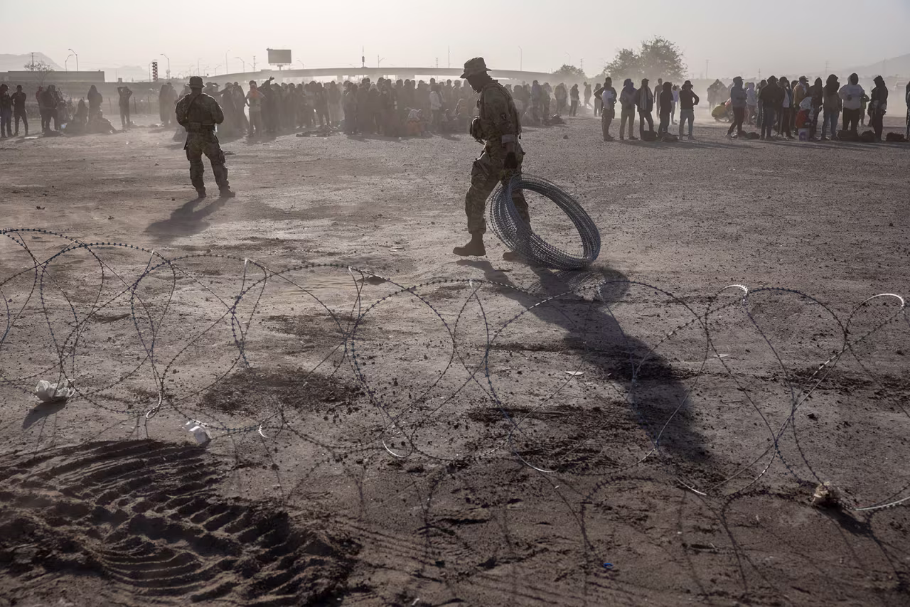 Texas National Guard soldiers place razor wire at a makeshift migrant camp located between the Rio Grande and the US-Mexico border fence on Thursday.