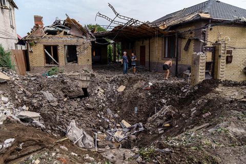 Debris is cleared next to a crater caused by a rocket strike on a house in Kramatorsk, Ukraine, Friday, August 12.