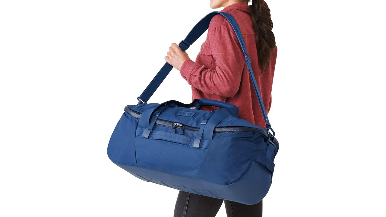 A photo of a person carrying a blue Yeti Crossroads 60L Duffel Bag