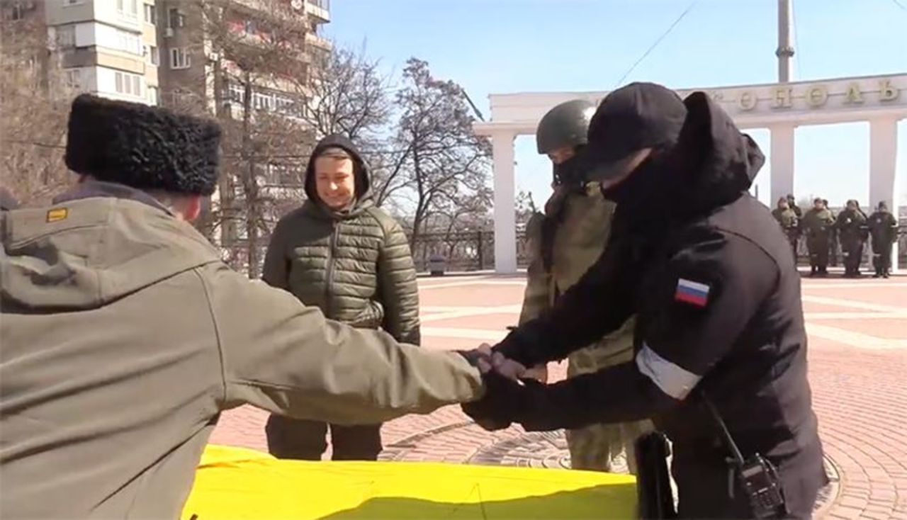 Russian troops and armed individuals were seen on the video writing on the flag, "From the Ministry of Defense of the Russian Federation...the Russian National Guard...the people's militia...the Cossacks."