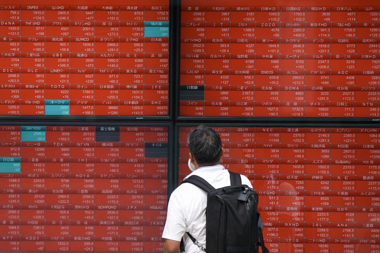 A man looks at an electronic quotation board displaying stock prices of Nikkei 225 on the Tokyo Stock Exchange in Tokyo on August 6.