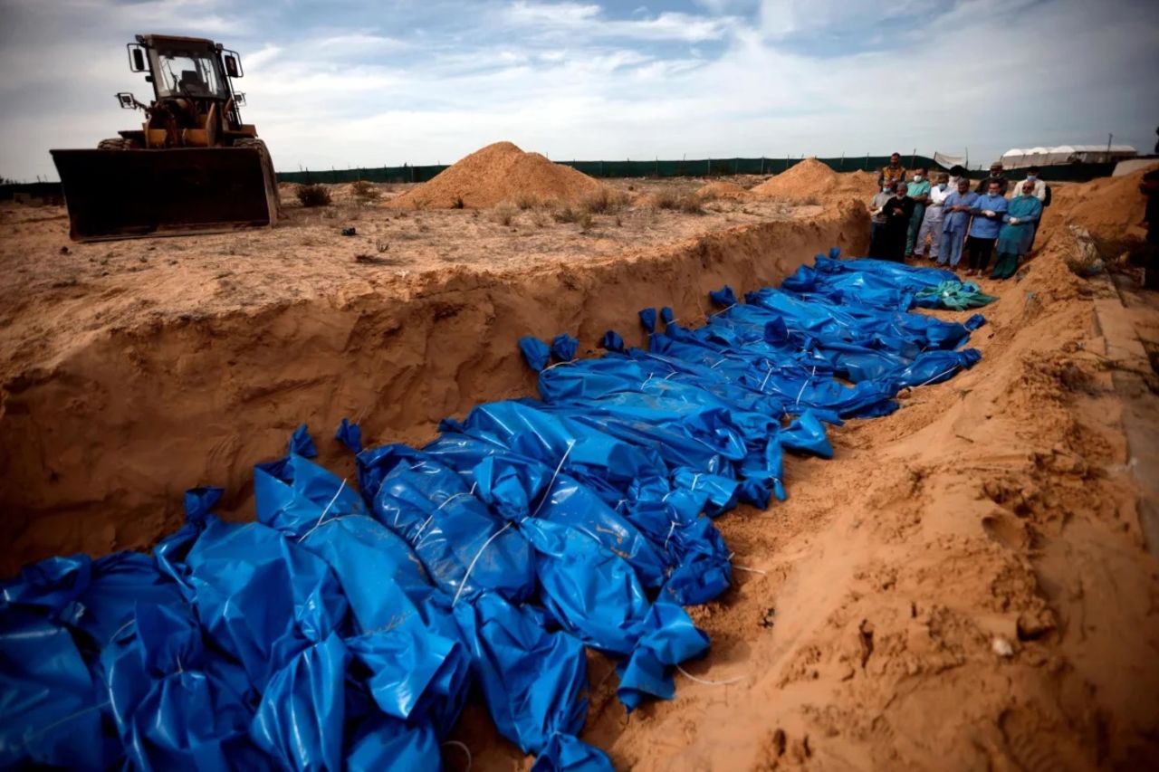 Palestinians pray over bodies in a mass grave in the town of Khan Younis, Gaza, on November 22.