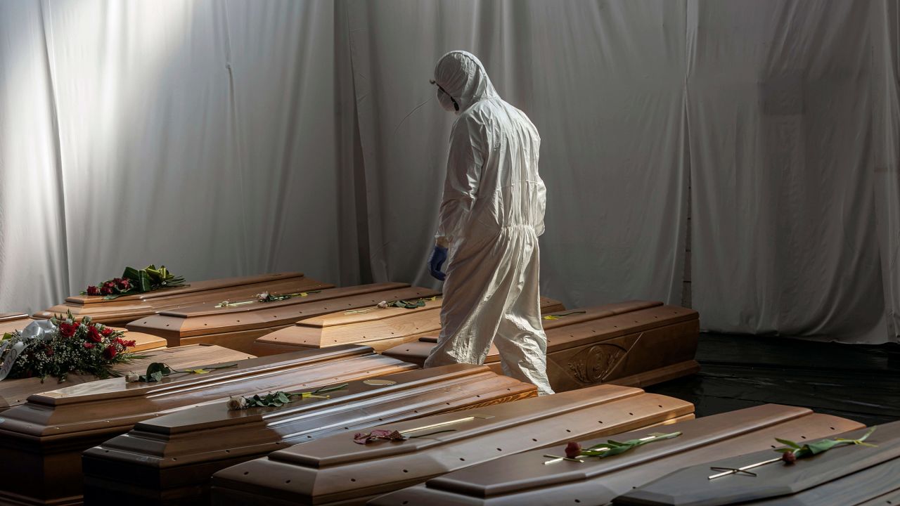 A Civil Protection member walks past the coffins of Covid-19 victims in Ponte San Pietro, Italy, on April 7, 2020.