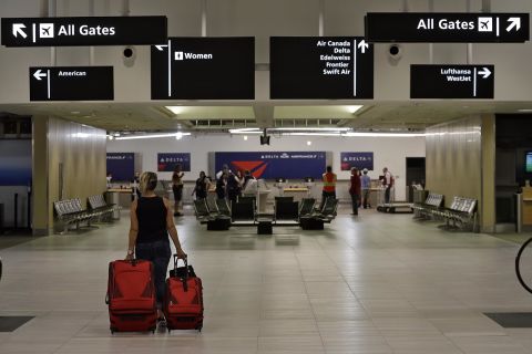 A passenger carries her luggage through a nearly deserted terminal at the Tampa International Airport on Friday, April 24.