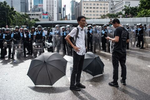 Pro-democracy lawmaker Eddie Chu (L) and Jeremy Tam (R) stand before a police line on Harcourt Road outside the government headquarters after the annual flag raising ceremony to mark the 22nd anniversary of the city's handover from Britain to China, in Hong Kong on July 1.