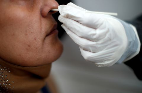A healthcare worker conducts a nasal swab test for COVID-19 from inside a freestanding coronavirus testing isolation booth at a hospital in Buenos Aires, Argentina, Monday, October 19.