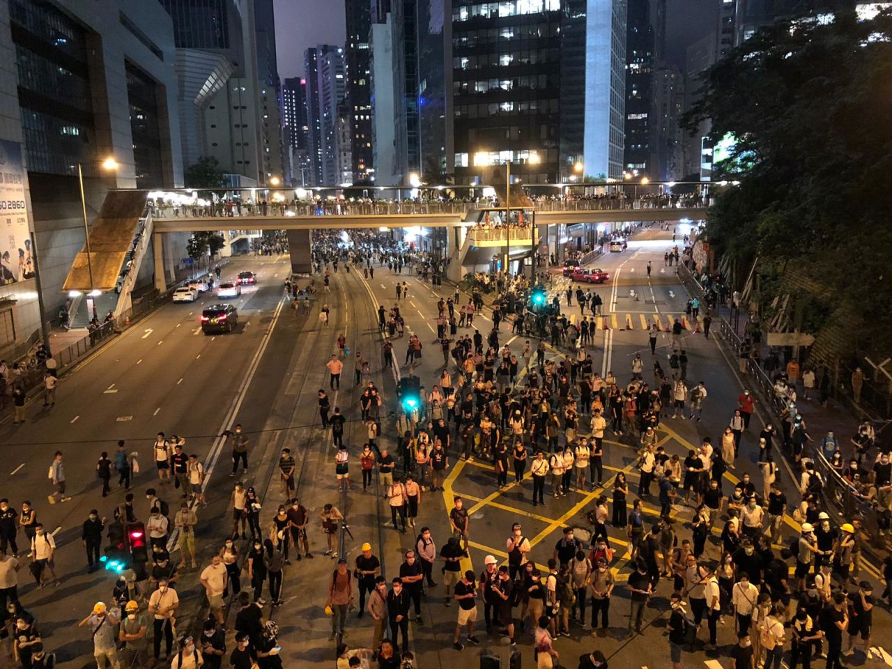 Protesters gather by on Queensway as police look on.