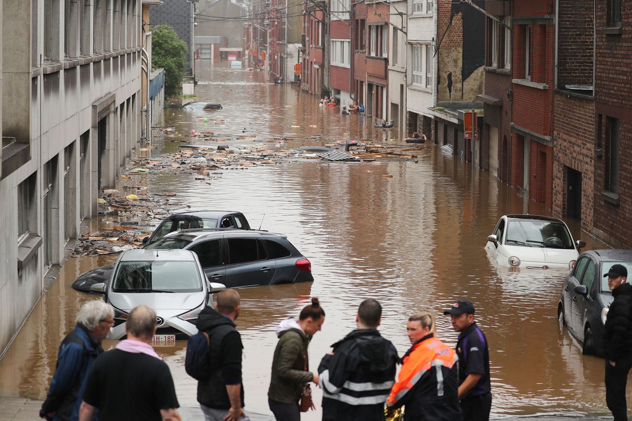 People stands in a flooded street following heavy rains in Liege, on July 15.