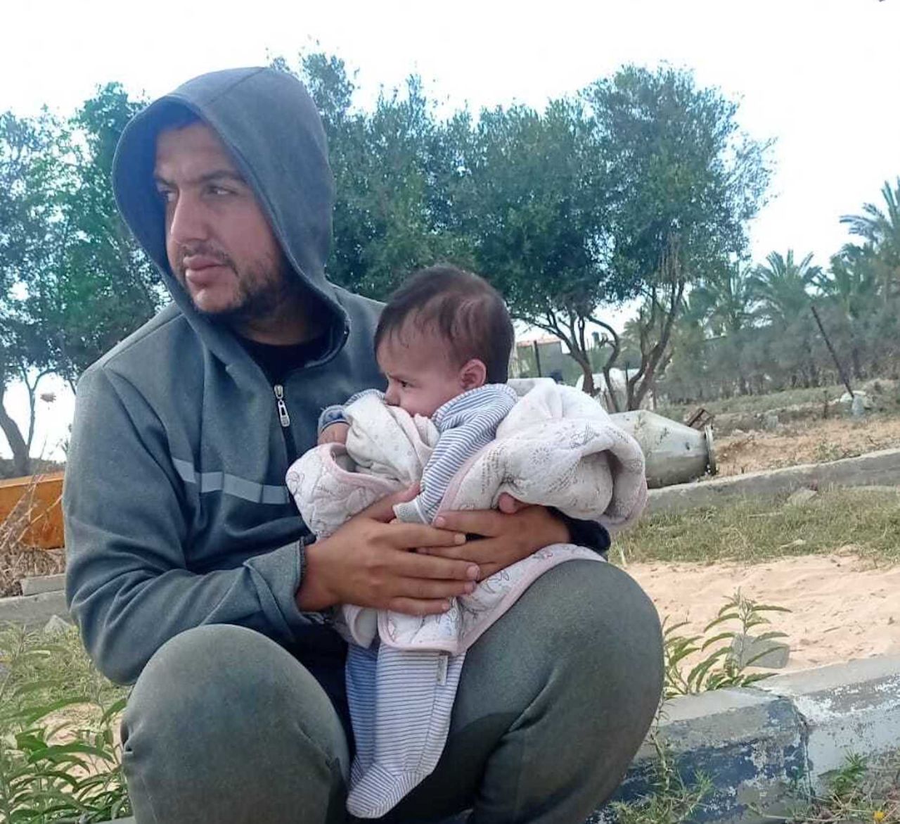 Raed Redwan (left) and his two-month-old baby, Maria (right) sit along Salah Al-Din Street, in central Gaza, in a photo shared with CNN on May 12