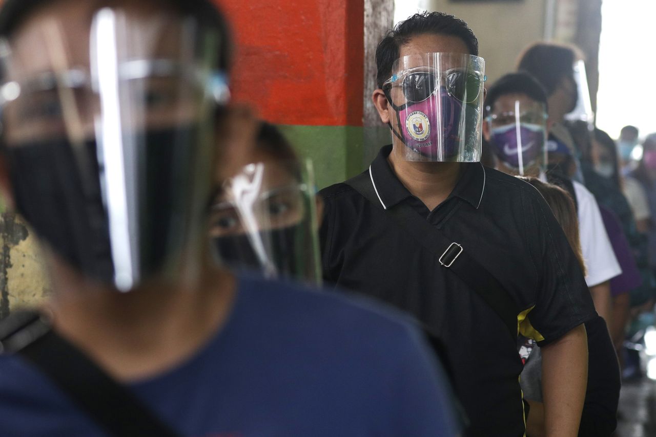 People wearing face mask and face shields to help curb the spread of COVID-19 line up for a bus ride in Caloocan city, Philippines, on Wednesday, August 19. 