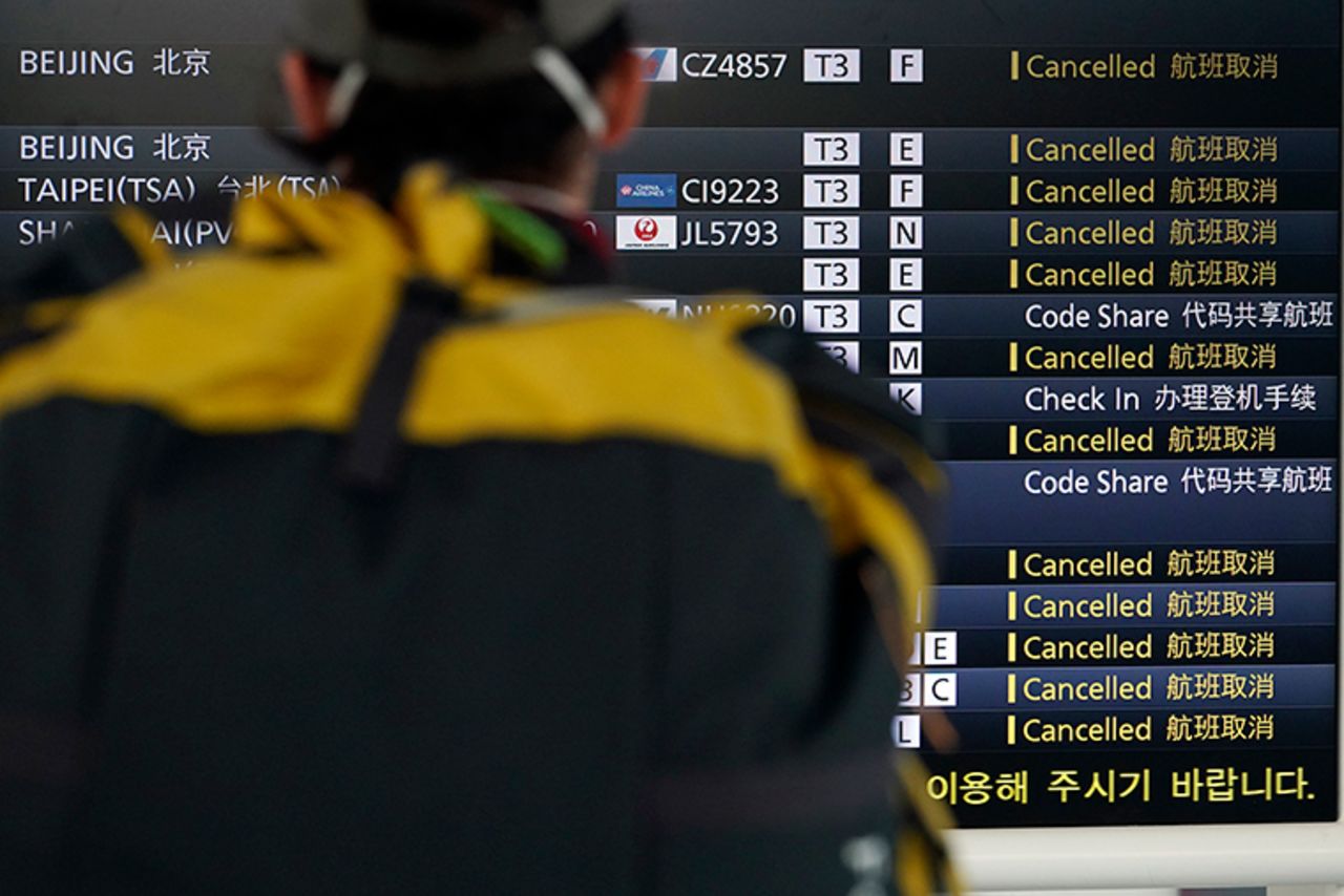 A traveler looks at canceled flights on a schedule board, some due to the coronavirus, at the Haneda International Airport in Tokyo, Wednesday, March 18.