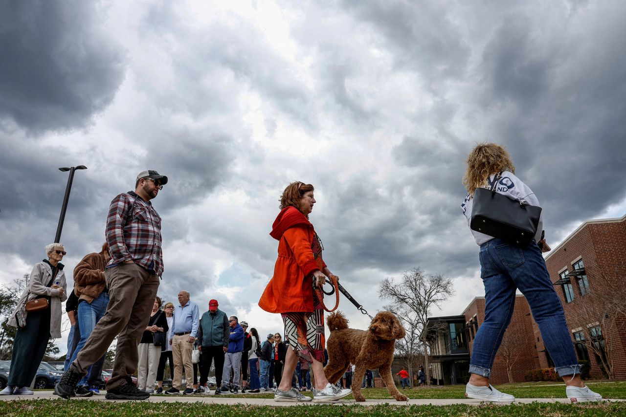 A woman with a dog stands in line to cast her vote in the South Carolina Republican presidential primary election at the Jennie Moore Elementary School in Mount Pleasant, South Carolina, on Saturday.