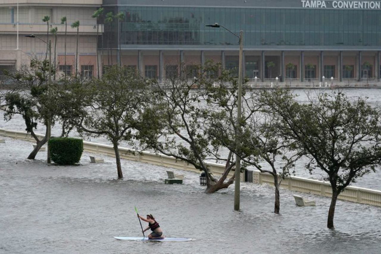 Zeke Pierce rides his paddle board down the middle of a flooded Bayshore Boulevard in Tampa, Florida on August 30, 2023.