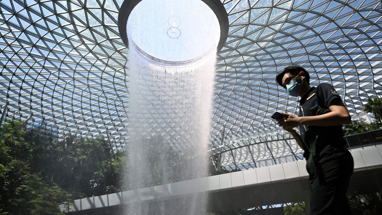 A man wearing a protective facemask walks past the Rain Vortex display at Jewel Changi Airport in Singapore on February 27.