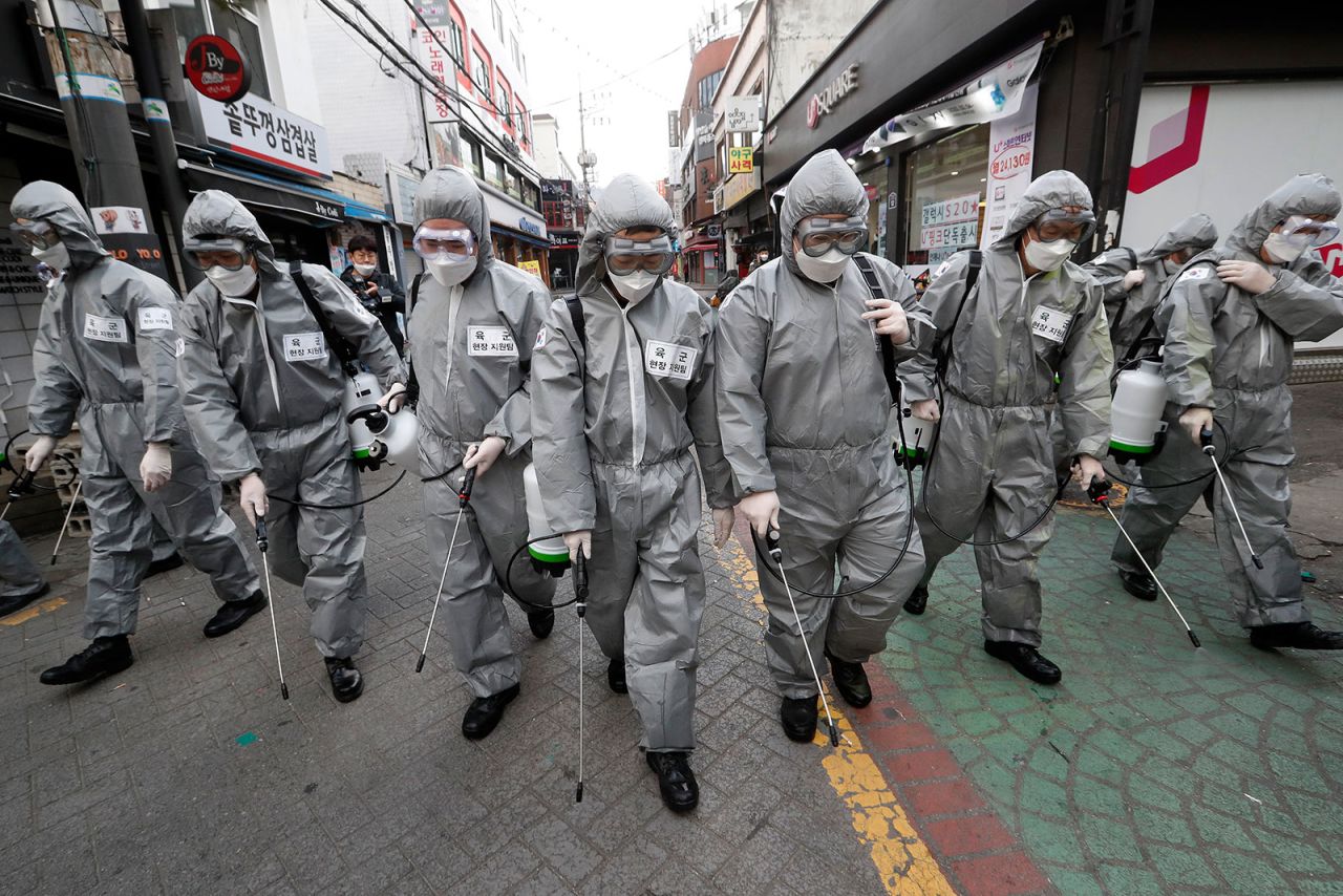 Army soldiers wearing protective suits spray disinfectant as a precaution against the new coronavirus at a shopping street in Seoul on March 4.