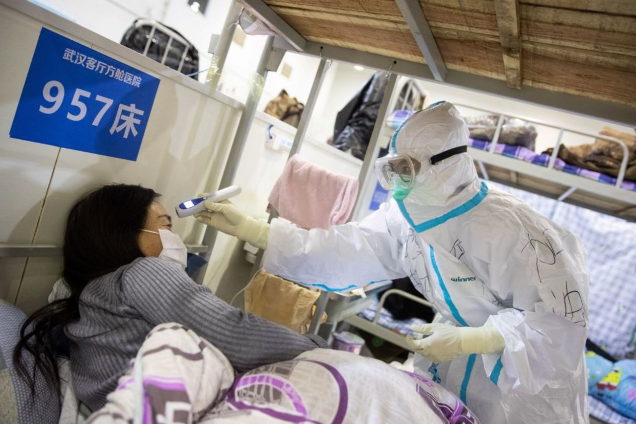 A medical worker checks the body temperature of a patient at an exhibition center converted into a hospital in Wuhan in China's central Hubei province on Friday, February 17.