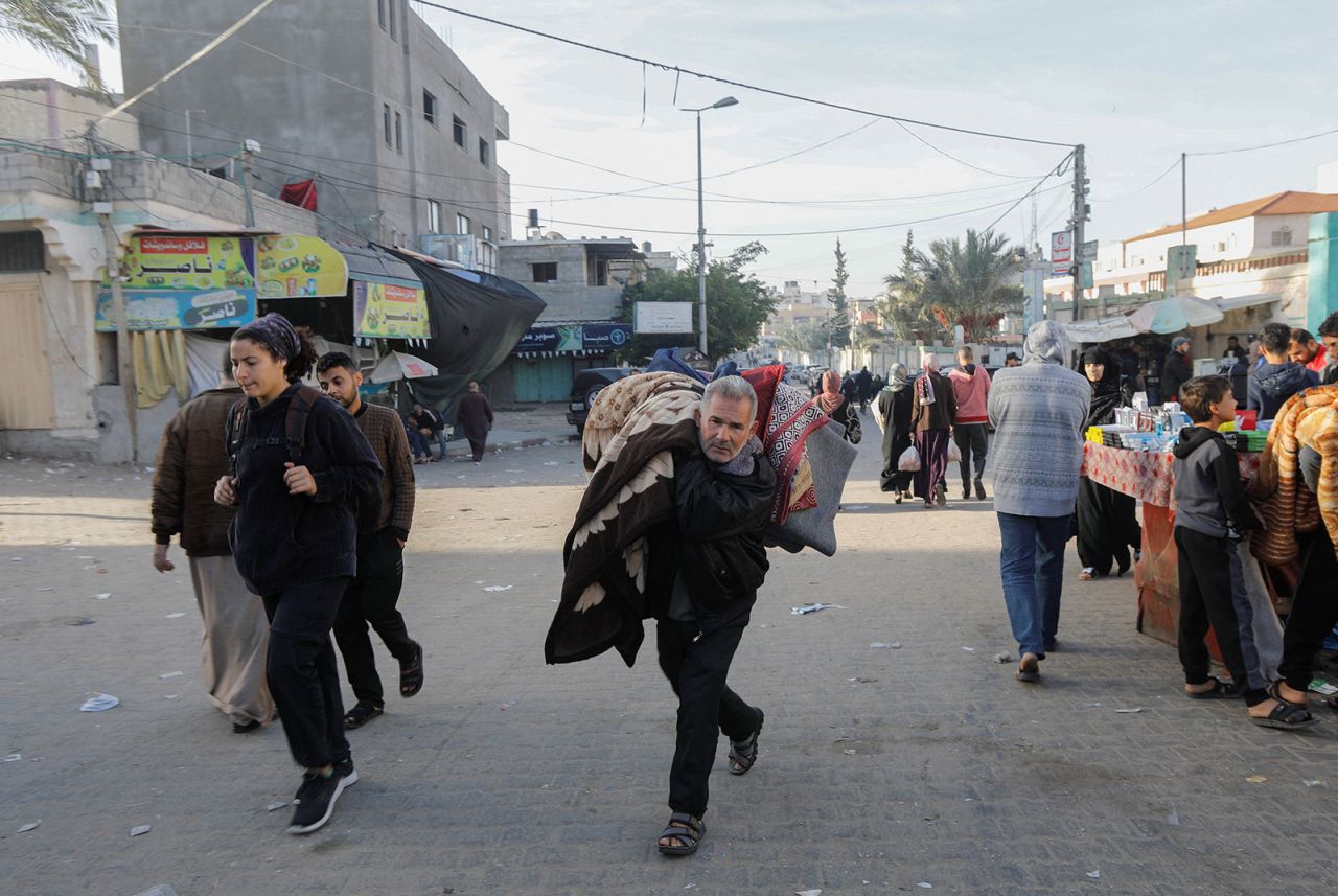 A displaced Palestinian man, who fled his house for safety, carries his belongings as he makes his way back to his home, during the  temporary truce. in Khan Younis in the southern Gaza, on Friday, Novemeber 24.