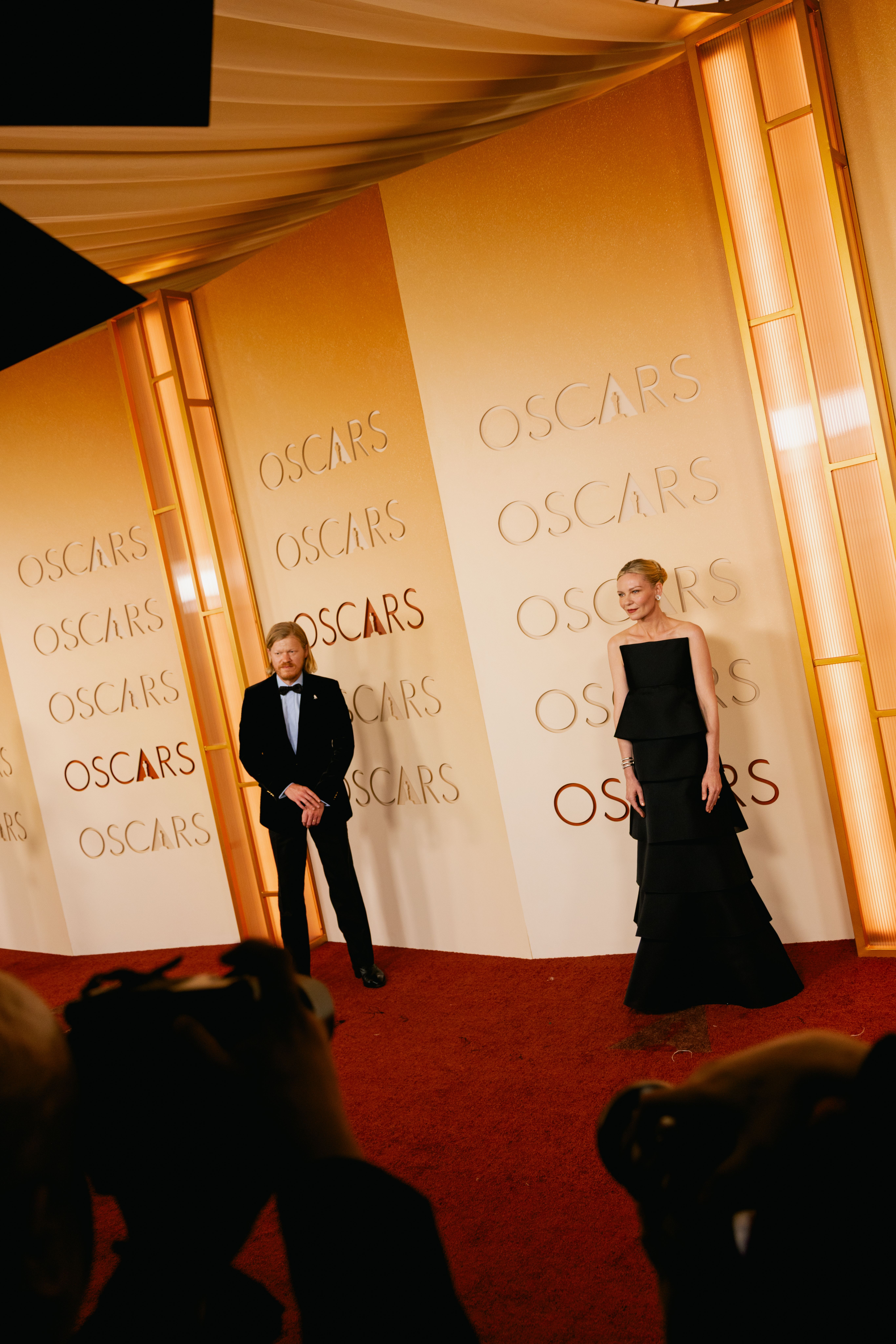 Kirsten Dunst poses in a tiered Celine dress as husband Jesse Plemons looks on.