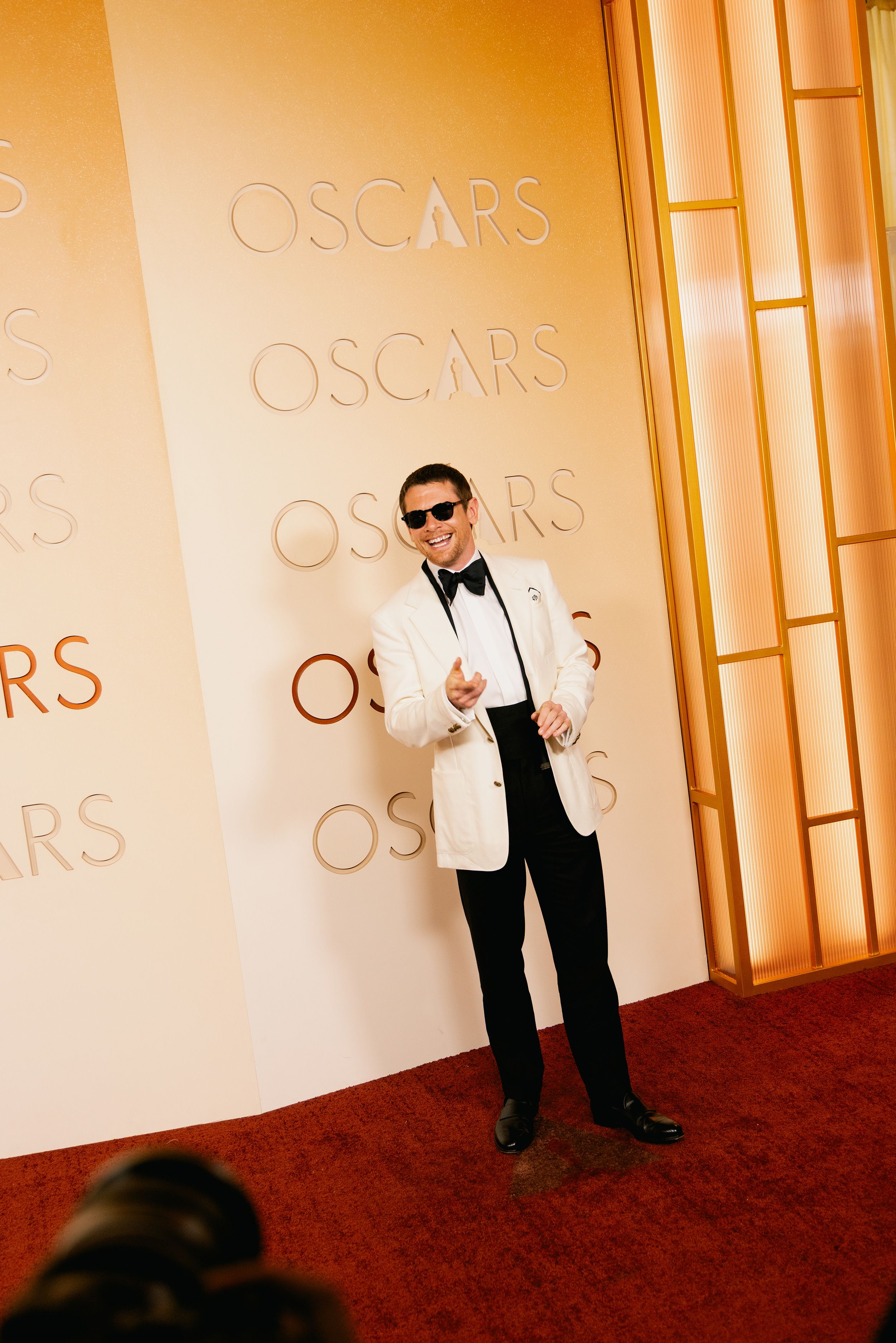 Jack O’Connell shows off his natural smile having arrived wearing a set of prosthetic vampire teeth, “Sinners” style.